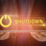 Imagen de una persona sosteniendo una laptop cerrada con la palabra "Shut Down" flotando sobre ella.